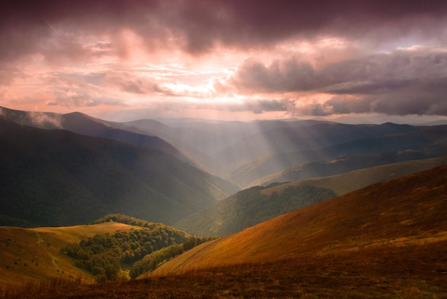 Cudowna panorama gór. Promienie słoneczne przenikają przez chmury pośrodku doliny.