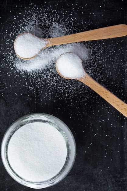 Zdjęcie cukier w drewnianych łyżkach i szklanym słoju
