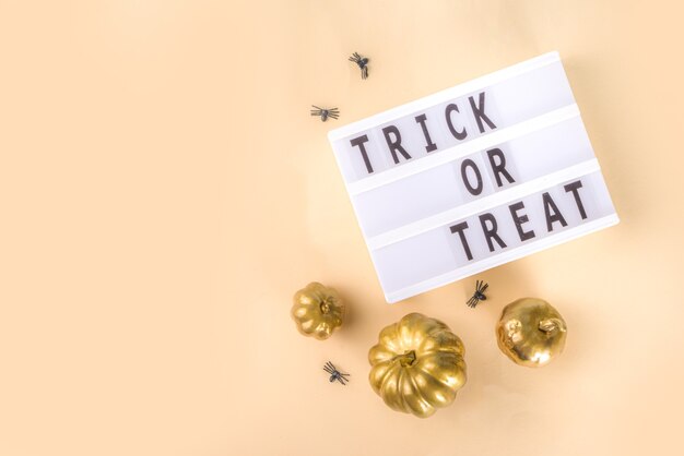 Cukierek Albo Psikus Tło, Prosta Kartka Z życzeniami Halloween, Party Zaproszenie Streszczenie Flatlay Ze Złotymi Kolorowymi Dyniami, Gwiazdami, Pająkami, Na Beżowym żółtym Tle Kopii Przestrzeni Widok Z Góry