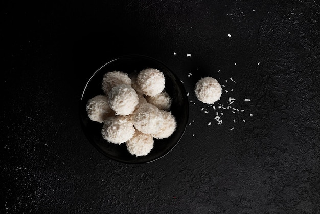 Cukierki kokosowe z orzechami na ciemnym tle Raffaello na czarnym tle Wysokiej jakości zdjęcie