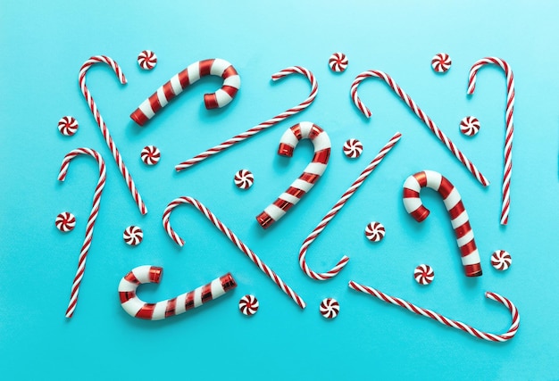 Cukierki na niebieskim tle Boże Narodzenie tradycyjne czerwono-białe paskowe cukierki z płaskim wzorem