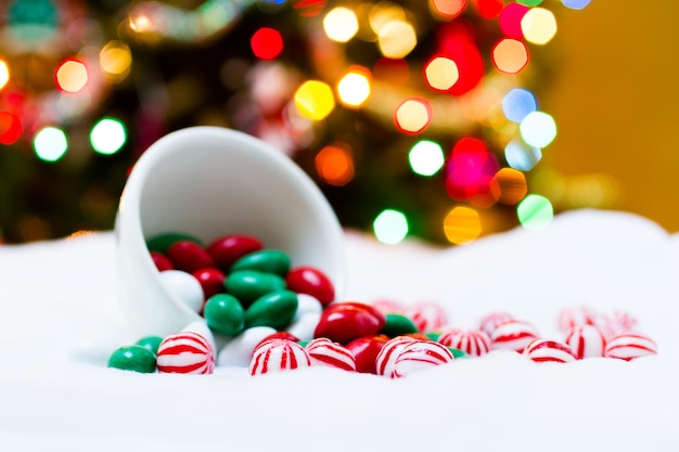 Cukierki świąteczne rozlane z kubka na białym tle