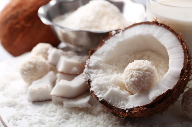 Cukierki w płatkach kokosowych i świeży kokos na kolorowym drewnianym tle