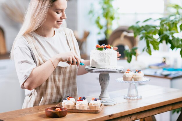 Cukiernik cukiernik młoda kaukaska kobieta z ciastem na stole kuchennym