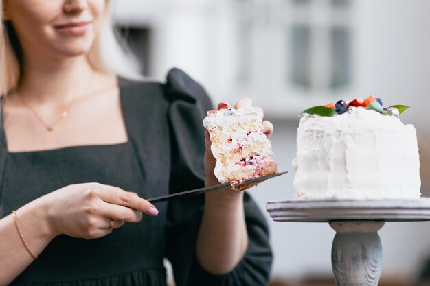 Cukiernik cukiernik młoda kaukaska kobieta z ciastem na stole kuchennym