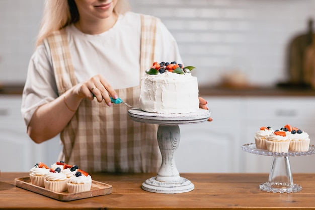 Cukiernik cukiernik młoda kaukaska kobieta z ciastem na stole kuchennym