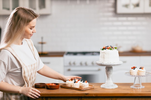 Cukiernik cukiernik młoda kaukaska kobieta z ciastem na stole kuchennym