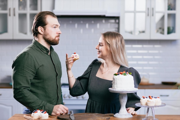 Cukiernik cukiernik młoda kaukaska kobieta z mężem chłopakiem mężczyzna spróbuj smaku ciasta na kuchennym stole Ciasta babeczki i słodki deser