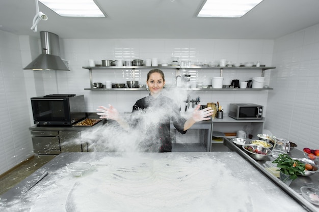Zdjęcie cukiernik klaszcze w dłonie, a mąka rozsypuje się po całej kuchni.