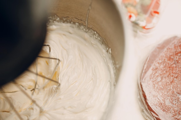 Cukiernik robi ciasto i robienie śmietany na blenderze. Gotowanie i dekorowanie deserów.