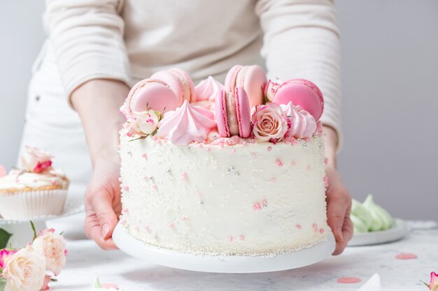 Cukiernik Stawia Piękny Biały Tort Z Makaronikami I Różami Na Stole