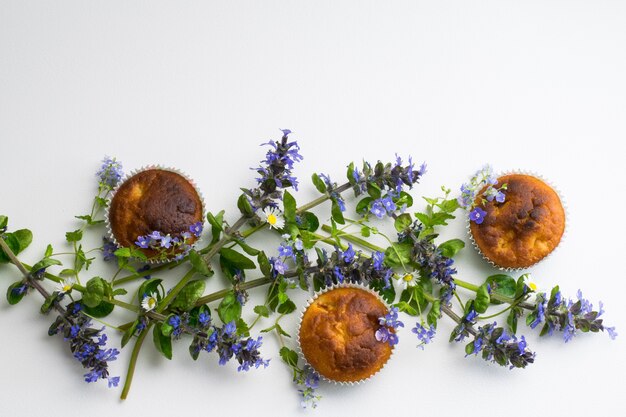 Zdjęcie cupcakes na białym tle ozdobione kwiatami pola