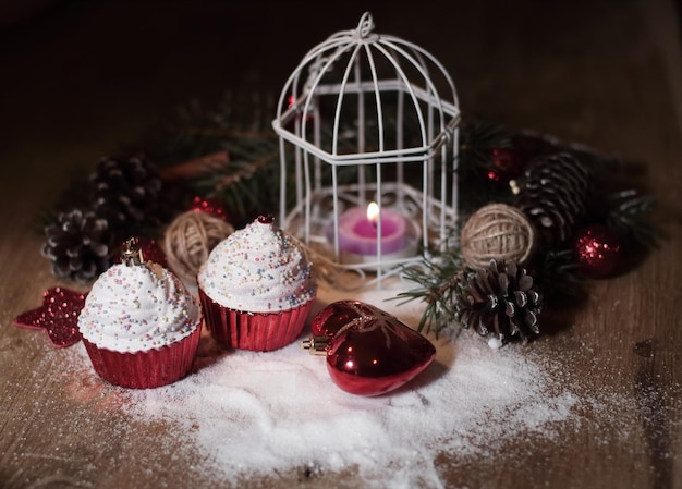 CupcakesŚwieca bożonarodzeniowa i ozdoby świąteczne na drewnianym tle