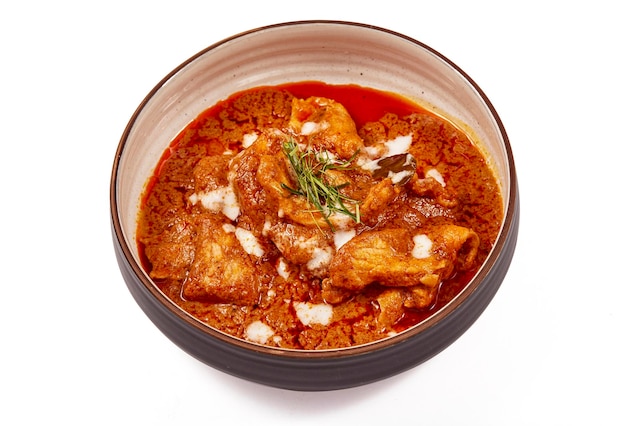 Curry wieprzowe Panang z mlekiem kokosowym i pokrojonymi liśćmi limonki kaffir w misce na białym tle Curry Panang to bardzo popularne danie tajskie