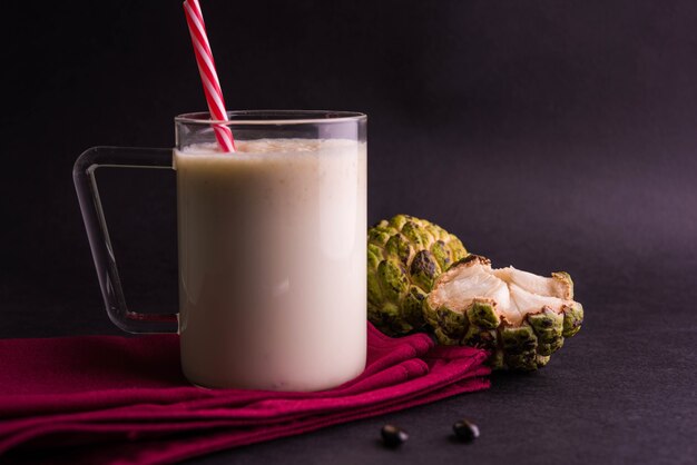 Custard Apple Lub Sitafal Milk Shake Podawane W Szklance Z Całymi Owocami Na Nastrojowym Tle. Selektywne Skupienie