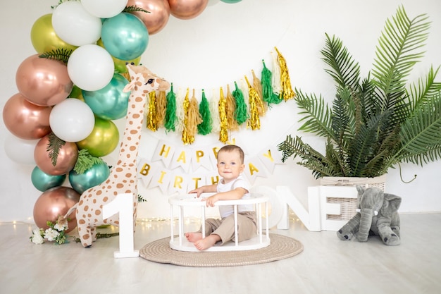 Cute baby boy kid świętuje swoje pierwsze urodziny na tle jasnych kolorowych balonów i świątecznych rekwizytów pierwsze wakacje dla dzieci