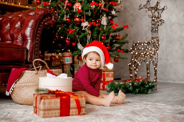 Cute Baby Santa Siedzi W Domu W Pobliżu Choinki Z Prezentami