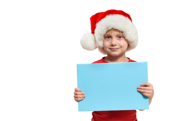 Cute boy w kapeluszu Santa z pustą niebieską tablicą w dłoniach Izolowanie na białym tle