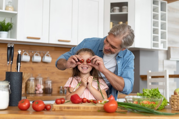 Cute dziewczynka i jej przystojny tata bawią się podczas gotowania w kuchni w domu.