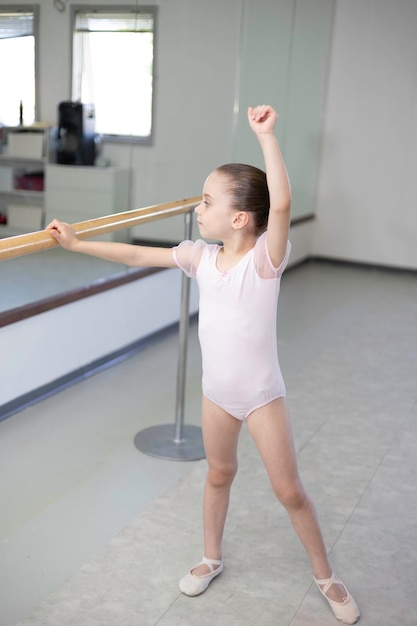 Cute dziewczynka maluch baleriny w bladoróżowe tutu i baletki ćwiczących ruchy taneczne.