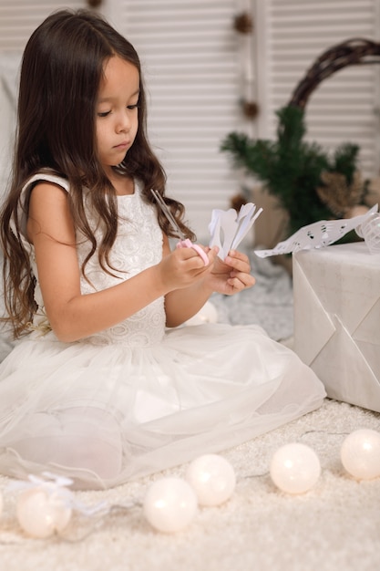 Cute dziewczynka sprawia, że papierowe płatki śniegu do dekoracji choinki w domu