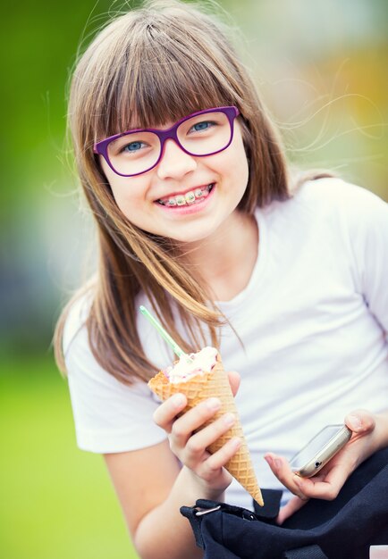 Cute Dziewczynka W Parku W Słoneczny Dzień Z Lodami I Telefonem Komórkowym.