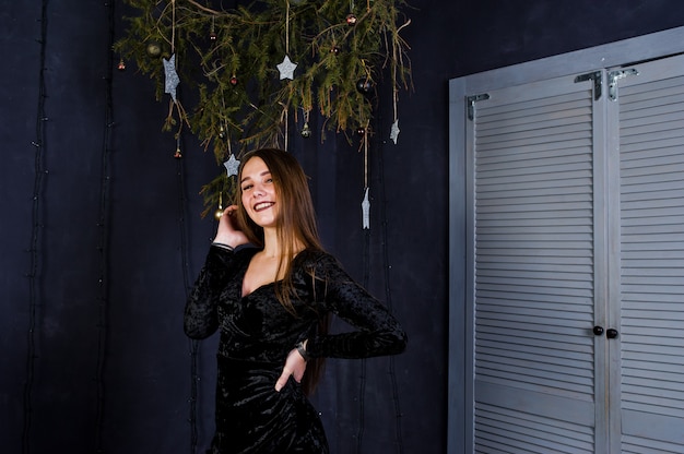 Cute girl nosić na czarnej sukience przed świąteczną dekoracją.
