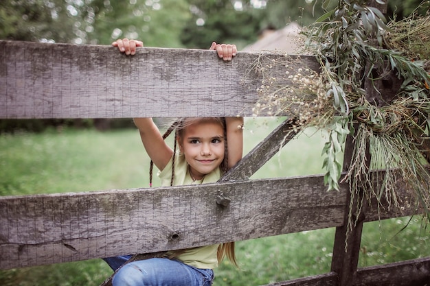 Cute girl noszenie wieniec kwiatów letnich i złotej pszenicy na podwórku domu na wsi