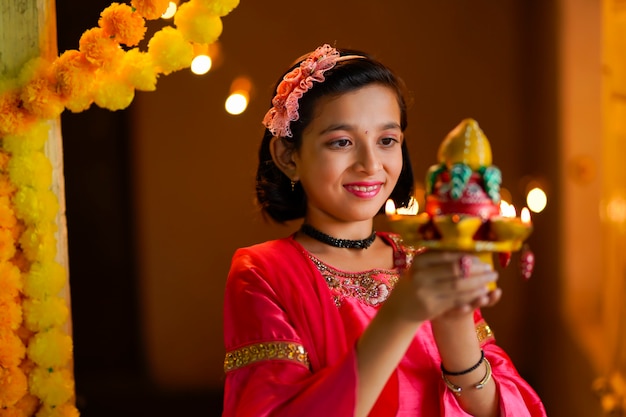 Cute Indian dziewczynka trzymając lampy diya lub naftowe na obchody Diwali.