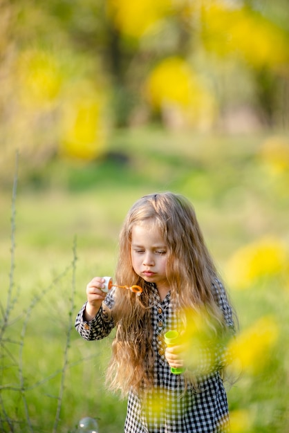 Cute little girl blondynka dmuchanie baniek mydlanych zabawy w parku wiosny.