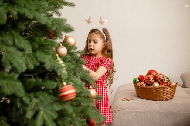 Cute little girl dekorowanie choinki w domu
