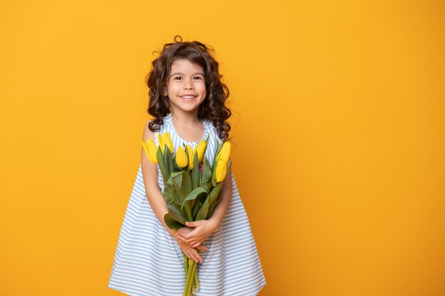 Cute Little Girl W Paski Sukienka Trzyma Bukiet Tulipanów Na żółtym Tle Studio