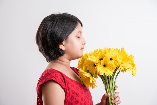 Cute Little Indian Girl trzyma kilka lub bukiet świeżych żółtych kwiatów Gerbera. Pojedynczo na białym tle