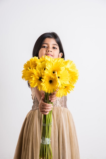 Cute Little Indian Girl Trzyma Kilka Lub Bukiet świeżych żółtych Kwiatów Gerbera. Pojedynczo Na Białym Tle