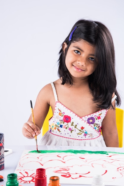 Cute little Indian lub Asian Girl korzystających Malowanie w domu za pomocą papieru, akwareli i pędzla artystycznego. Selektywne skupienie
