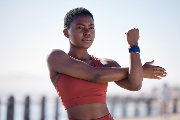 Ćwiczenia fitness i czarna kobieta rozciągająca się w mieście dla zdrowego stylu życia, odnowy biologicznej i treningu cardio Motywacja sportowa i lekkoatletka gotowa do rozpoczęcia treningu maratonu i joggingu nad morzem