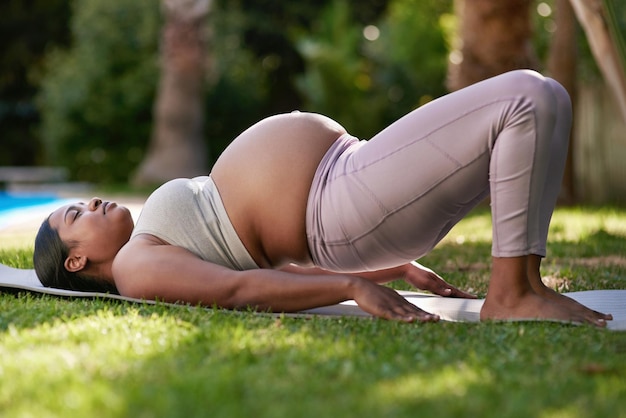 Ćwiczenia o niskim wpływie są świetne dla kobiet w trzecim trymestrze Ujęcie kobiety w ciąży uprawiającej jogę na zewnątrz