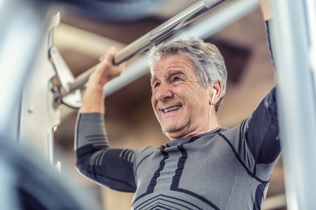 Ćwiczenie siły ramion przez starszego mężczyznę na maszynie fitness w sali gimnastycznej.