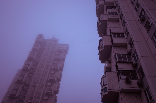 Cyberpunkowa stylistyka Dwa wysokie budynki mieszkalne zanurzone w mglistym fioletowym niebie