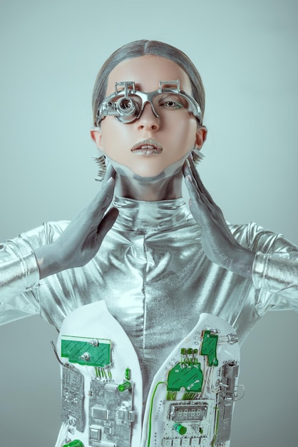 Cyborg dotykający szyi i patrzący na kamerę odizolowany na szarej koncepcji technologii przyszłości