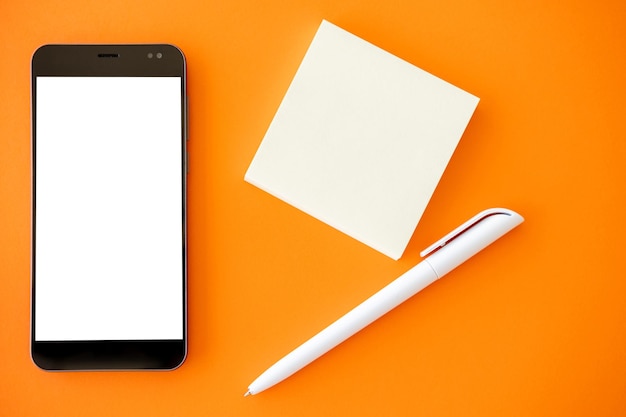 Cyfrowa makieta mobilna technologia robi notatki na smartfonie z białym pustym ekranem, małymi kartkami i długopisem