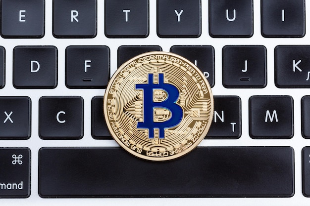 Cyfrowa waluta złota bitcoin, niebieska moneta na czarnej klawiaturze komputera. Zdjęcie w wysokiej rozdzielczości.