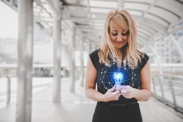 Zdjęcie cyfrowy kompozytowy obraz kobiety trzymającej oświetloną żarówkę elektryczną z ikoną