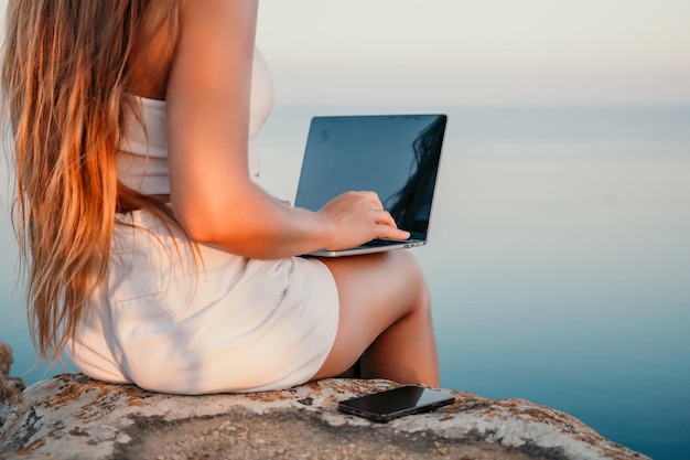 Cyfrowy nomad biznes kobieta pracuje na laptopie nad morzem ładna pani pisze na komputerze nad morzem