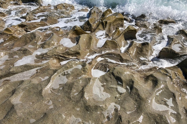 Zdjęcie cyfrowy obraz kamienistej plaży z rozbijającą się o nią wodą.