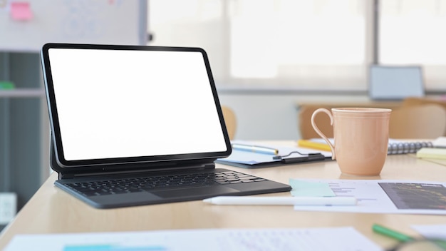 Cyfrowy tablet z filiżanką kawy z bezprzewodową klawiaturą i dokumentami finansowymi na biurku