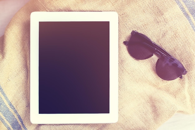 Cyfrowy tablet z okularami przeciwsłonecznymi na ręczniku plażowym