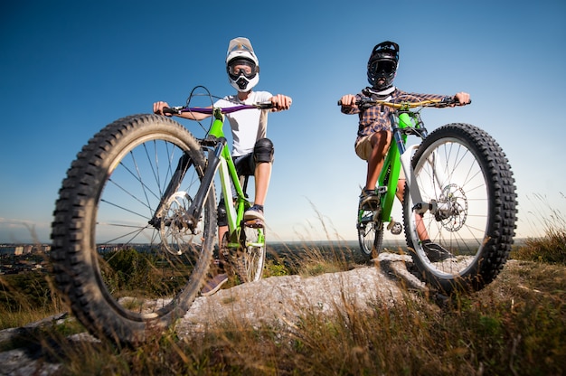 Cykliści z rowerami górskimi na wzgórzu pod niebieskim niebem