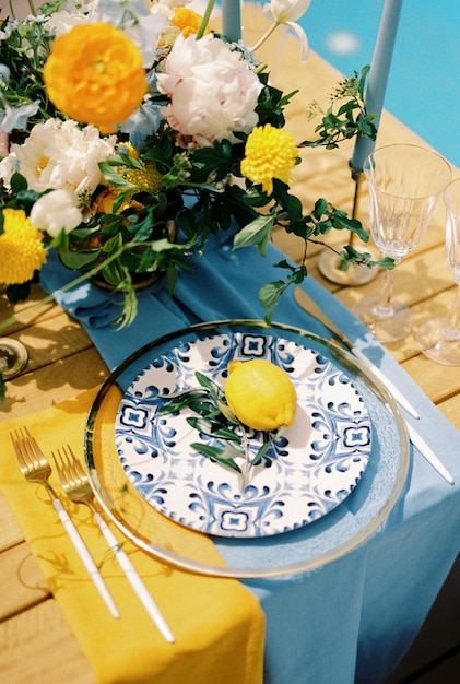 Zdjęcie cytryna i gałąź oliwkowa leżą na talerzu stojącym na niebieskiej i żółtej serwetce na stole świątecznym