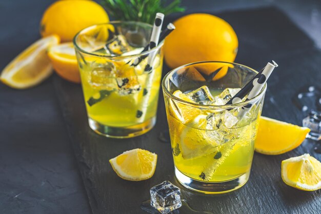 Cytrynowy koktajl alkoholowy z lodową cytryną i ziołem rozmarynu na czarnej kamiennej betonowej powierzchni Tradycyjny włoski domowy cytrynowy napój alkoholowy likier limoncello